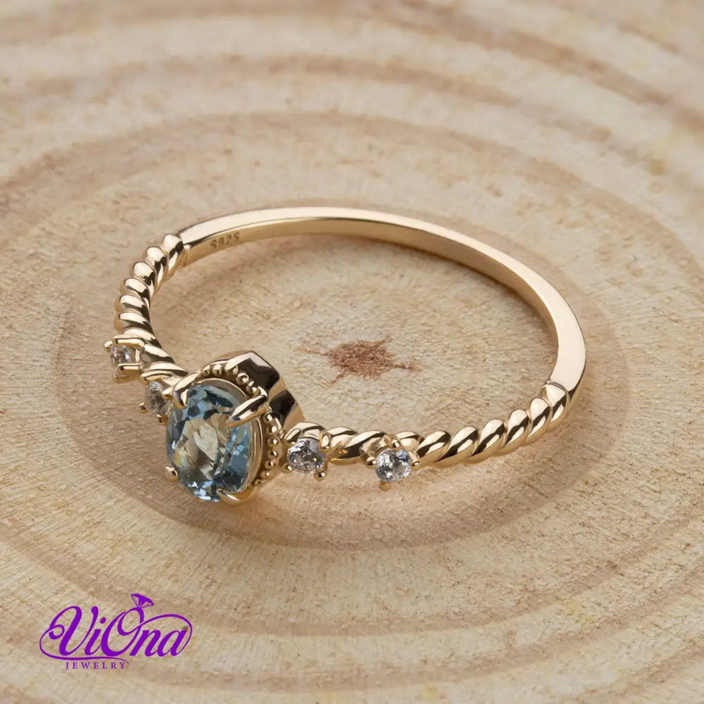 Oval Blue Topaz Gemstone Radiance: Gold-Plated 925 Sterling Silver Ring with 4 Side Stones and Intricate Rope Detailing